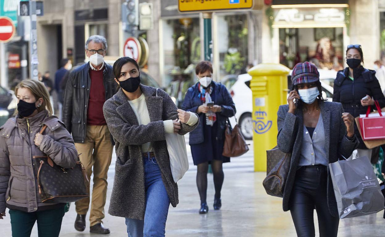 Varias personas con mascarilla pasean por Valencia. 