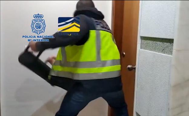 Un policía derriba una puerta. 