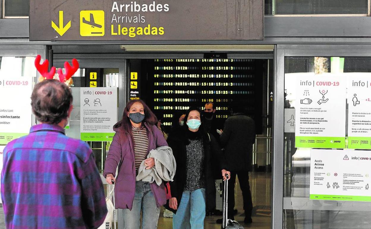 Un hombre con un tocado navideño espera ayer a las puertas del aeropuerto de Valencia la salida de un pasajero.