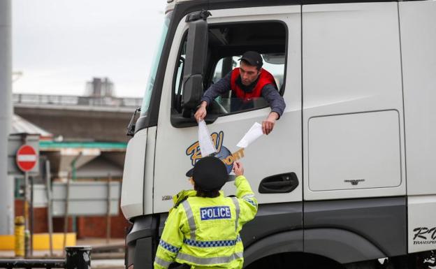 Un camionero muestra los papeles a un agente en la frontera. 