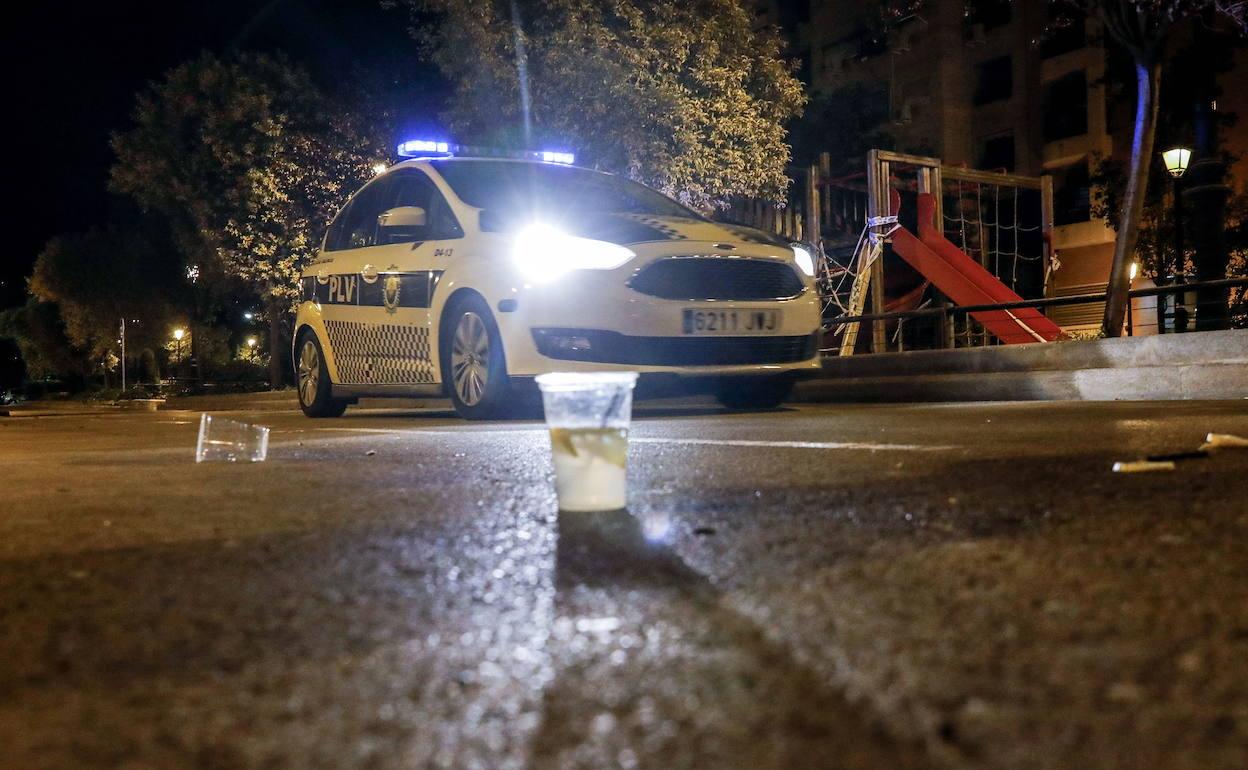 Una patrulla de la Policía Local junto a vasos de plástico por un botellón en Valencia. 