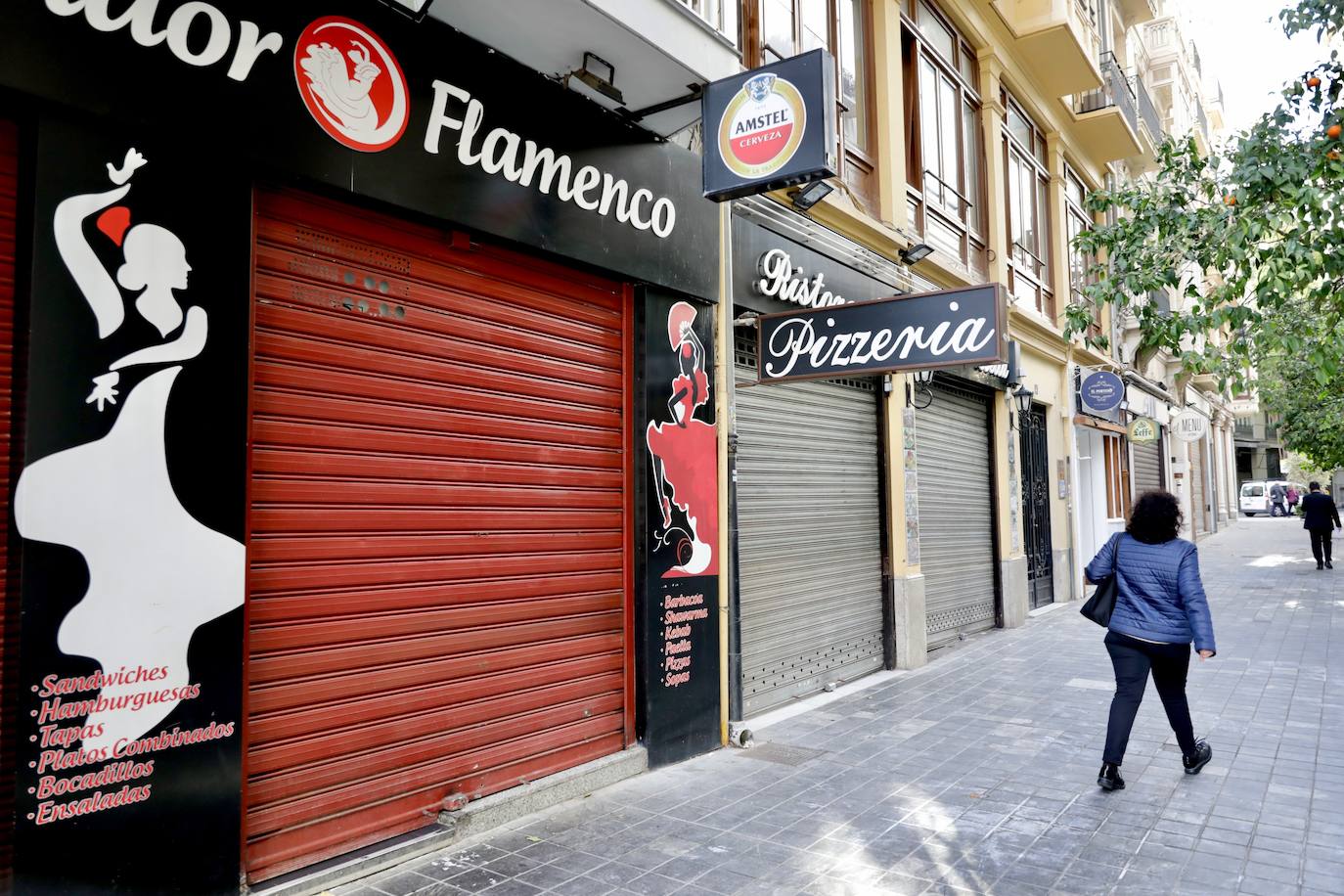 La hostelería de Valencia permanece totalmente cerrada, al menos durante los próximos 14 días, desde este jueves 21 de enero. Así lo estipulan las nuevas medidas tomadas por parte del Consell para tratar de frenar el avance de la pandemia de coronavirus en la Comunitat, que fueron anunciadas el pasado martes 19. La restricción deja multitud de persianas bajadas, en las que se ven algunos crespones negros en señal de protesta silenciosa, y calles sin terrazas ni vida en el centro de la ciudad. 