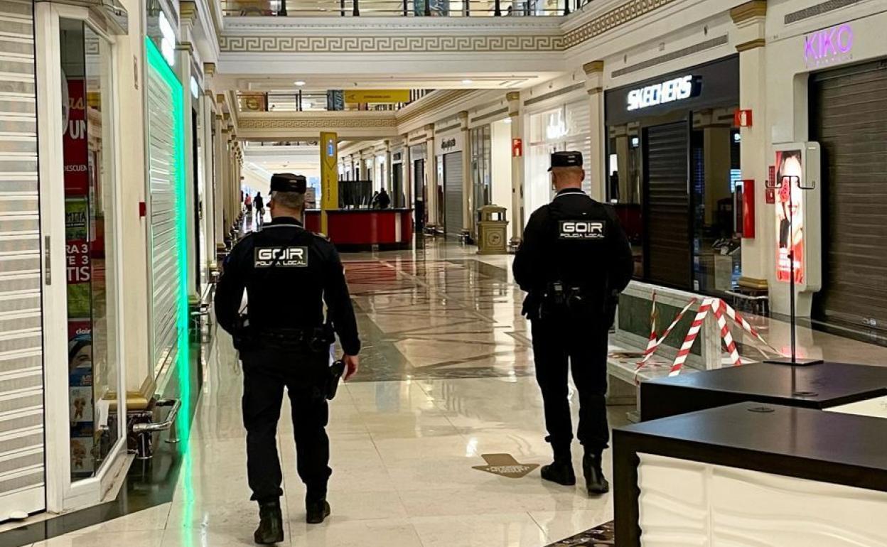 Dos agentes comprueban que los comercios están cerrados en un centro comercial siguiendo la nueva normativa del Consell. 