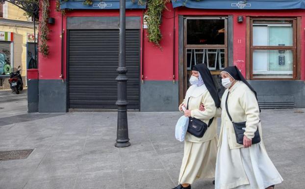 Dos monjas pasan por delante de un establecimiento cerrado en Madrid. 