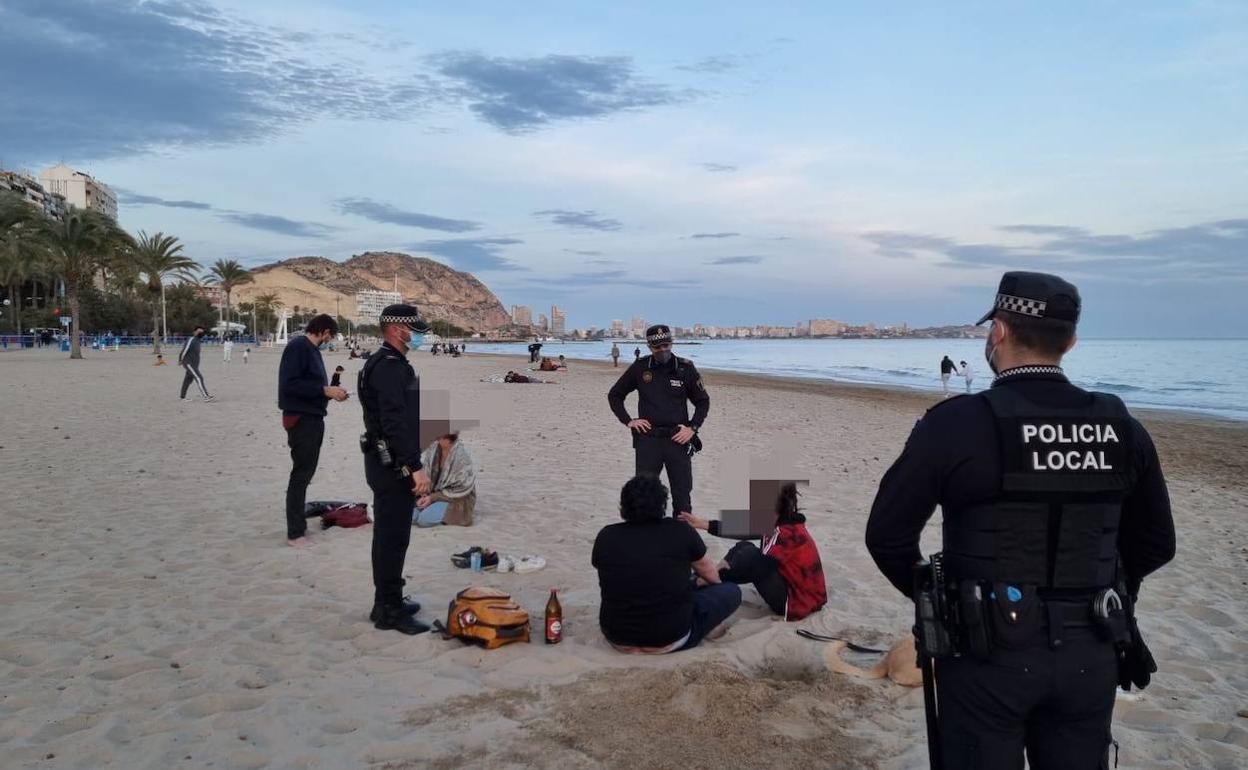 Agentes de la Policía Local de Alicante sorprenden a varios jóvenes compartiendo bebida en la playa. 