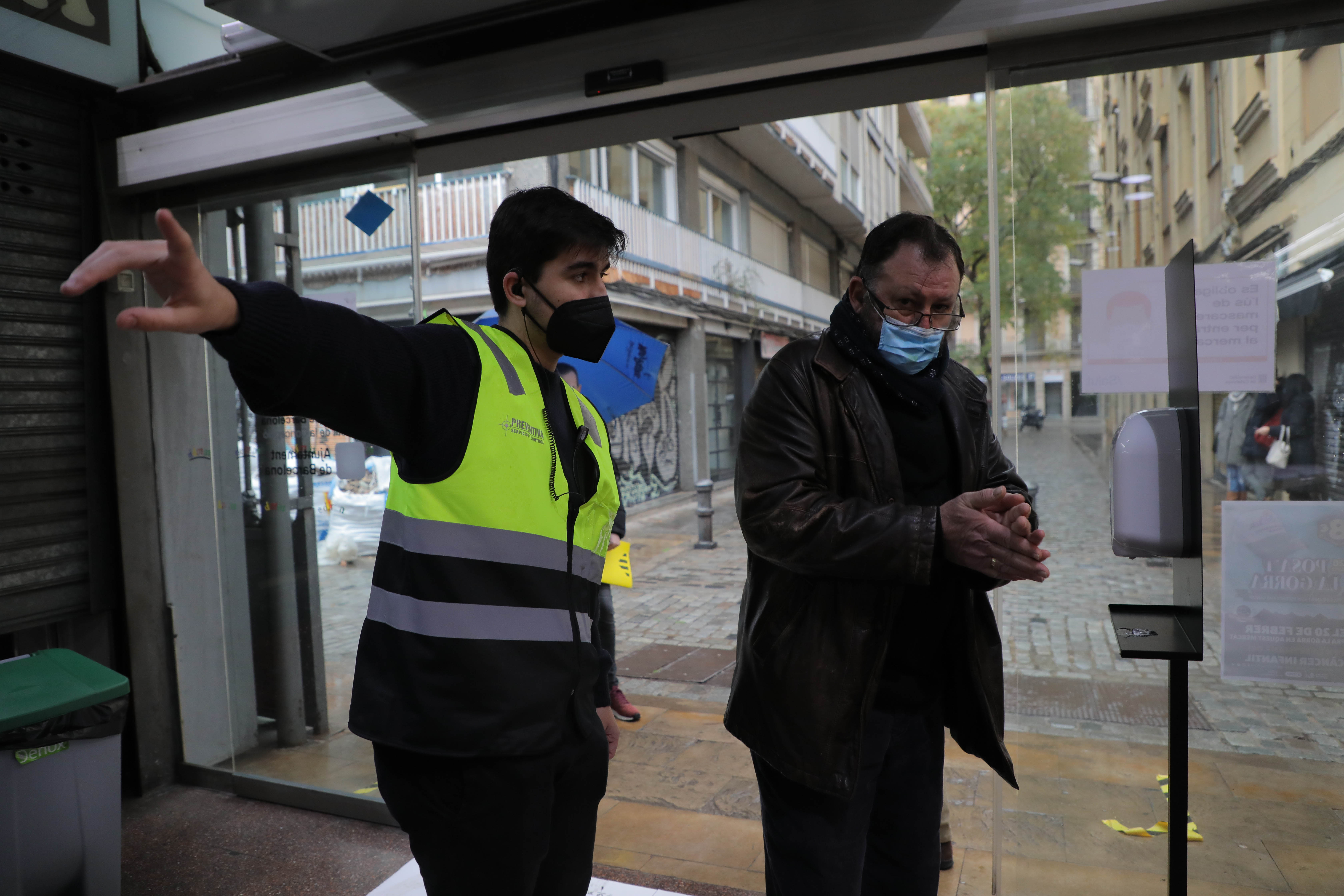 Un miembro de seguridad indica a una persona dónde tiene que situarse en una mesa electoral. 