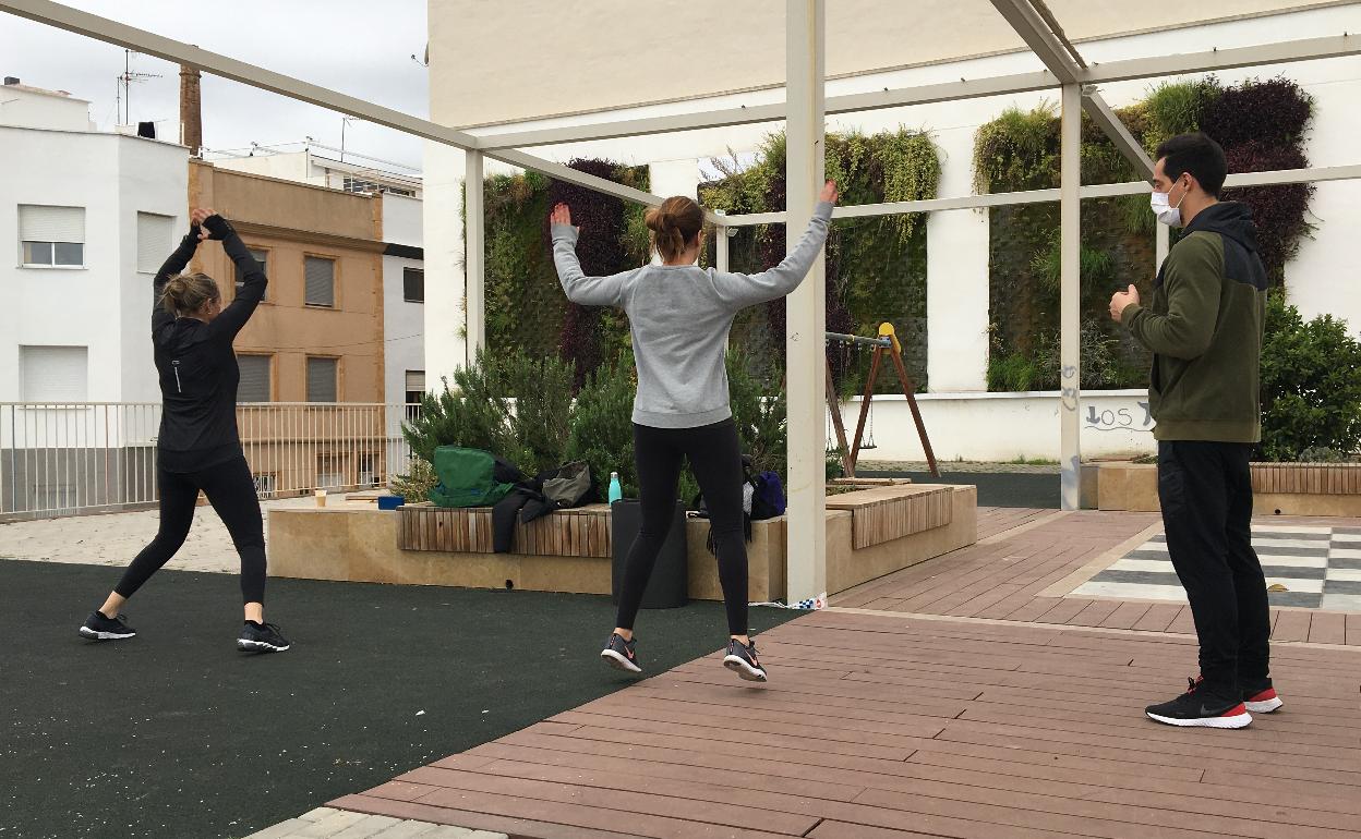 Javi Rees dirige una clase al aire libre con dos alumnas en la Plaza del Tirant de Gandia. 