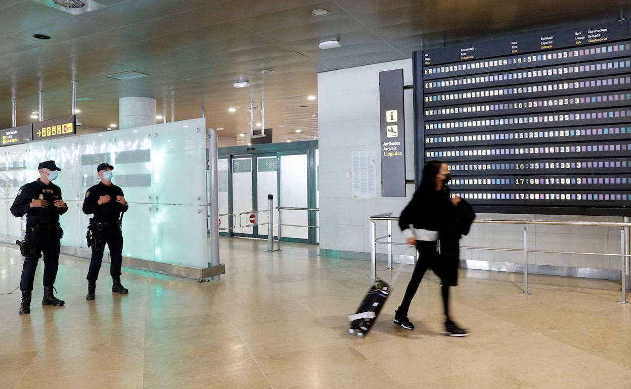 Dos agentes de la Policia Nacional vigilan la puerta de llegadas del aeropuerto de València.