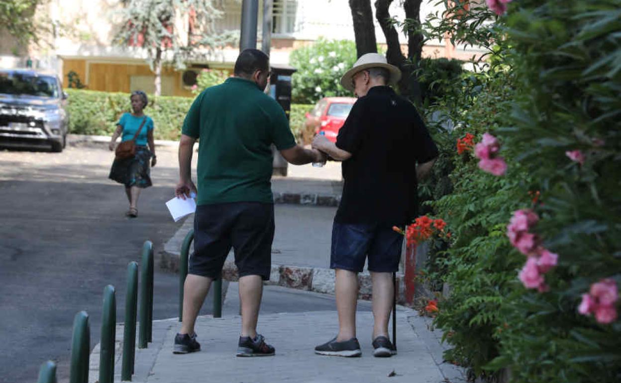 Un hombre, junto con un anciano en la calle.