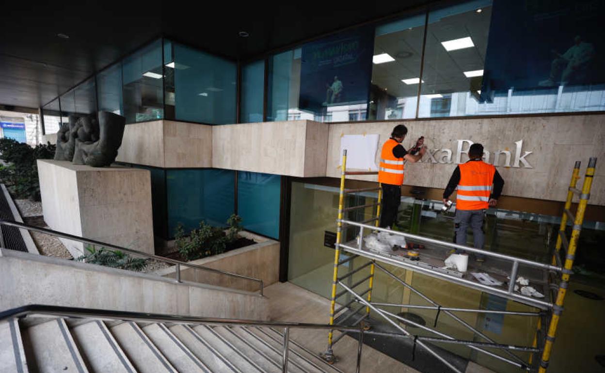 Operarios cambiando el letrero de Bankia por el de Caixabank en la sede de Pintor Sorolla.