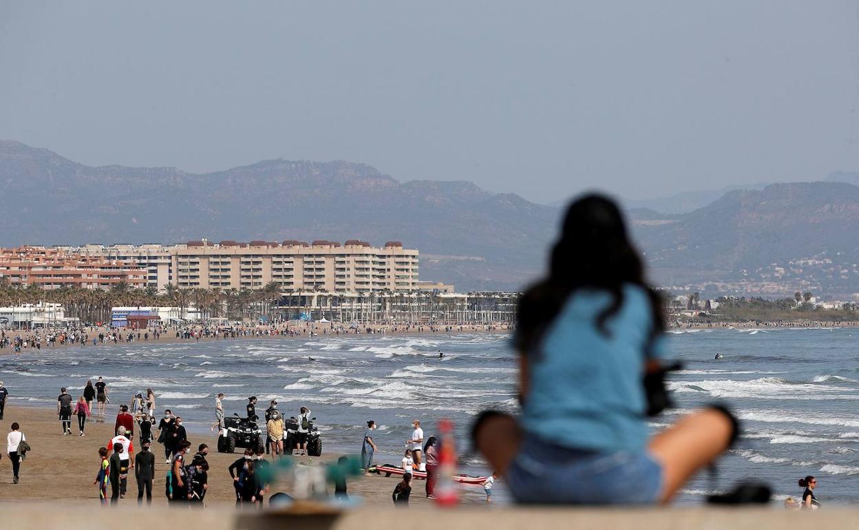 na joven observa la playa de Las Arenas desde el espigón de la Marina del Puerto de Valencia. 