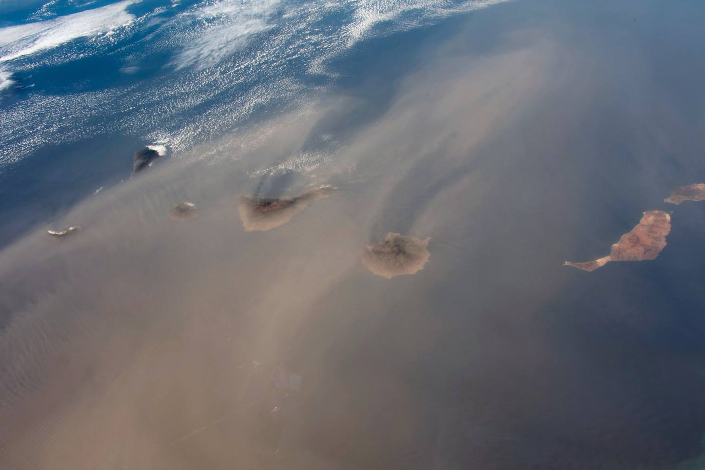 Los astronautas de la Estación Espacial Internacional muestran unas imágenes con detalle excepcional gracias al ángulo oblicuo con el que se tomaron las fotos, que resalta el relieve. Imagens del archipiélago Canario, que «se encontraba inmerso en una gran advección de polvo -o calima, como también se conoce en España- que enturbia las imágenes, pero muestra las islas surcando entre el polvo».