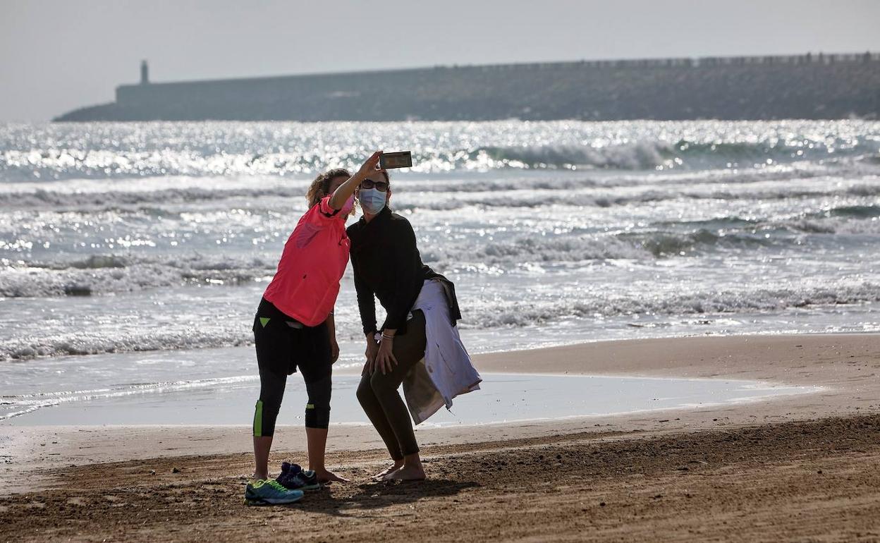 Dos chicas se hacen una foto en la playa.