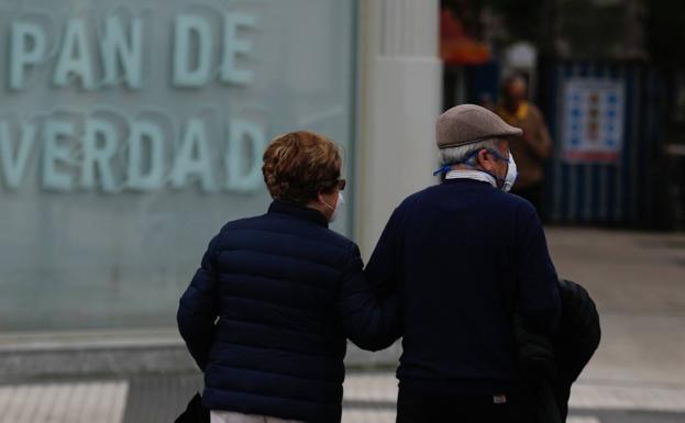 Una pareja de jubilados pasea por la calle. 