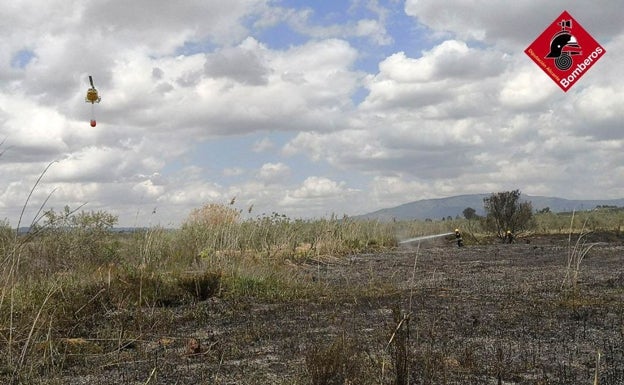 Bomberos a pie y un helicóptero transporta agua tratan de sofocar el incendio de Pinoso. 