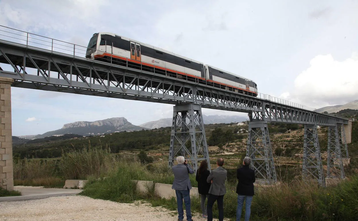 El conseller Arcadi España y la directora gerente de FGV observan el Pont del Quisi de Benissa mientras pasa un tren. 