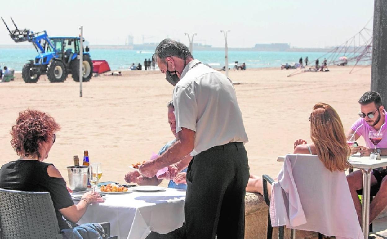 Varios clientes disfrutan de los espacios al aire libre, ayer por la mañana, en los restaurantes del Paseo Marítimo de Valencia. 