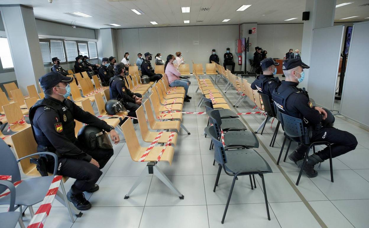 Varios polcías vigilan a los acusados de la reyerta mortal en la sala de vistas donde se celebra el juicio. 