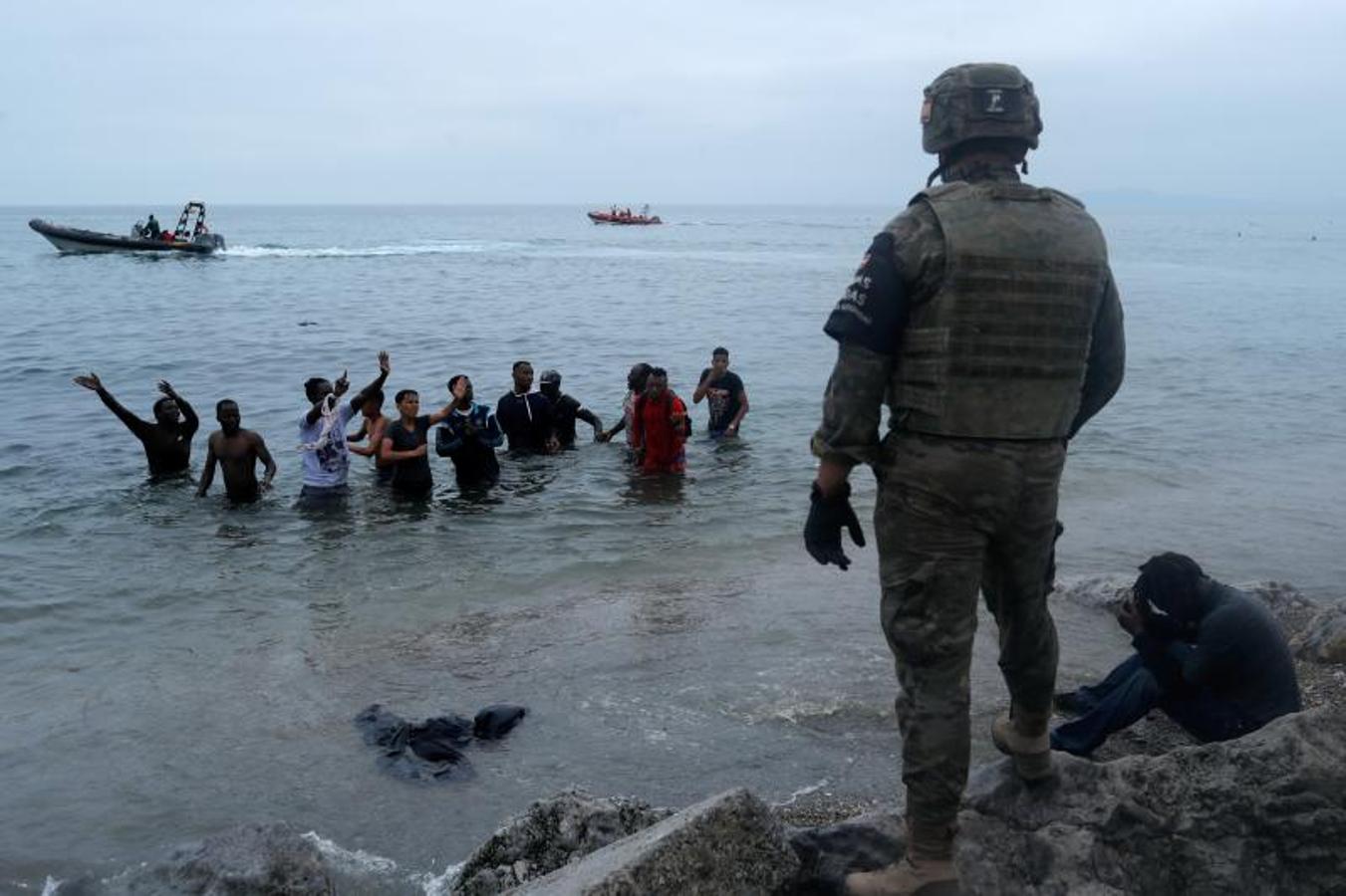 Un legionario español se para frente a ciudadanos marroquíes, después de que miles de marroquíes cruzaron la frontera hispano-marroquí.