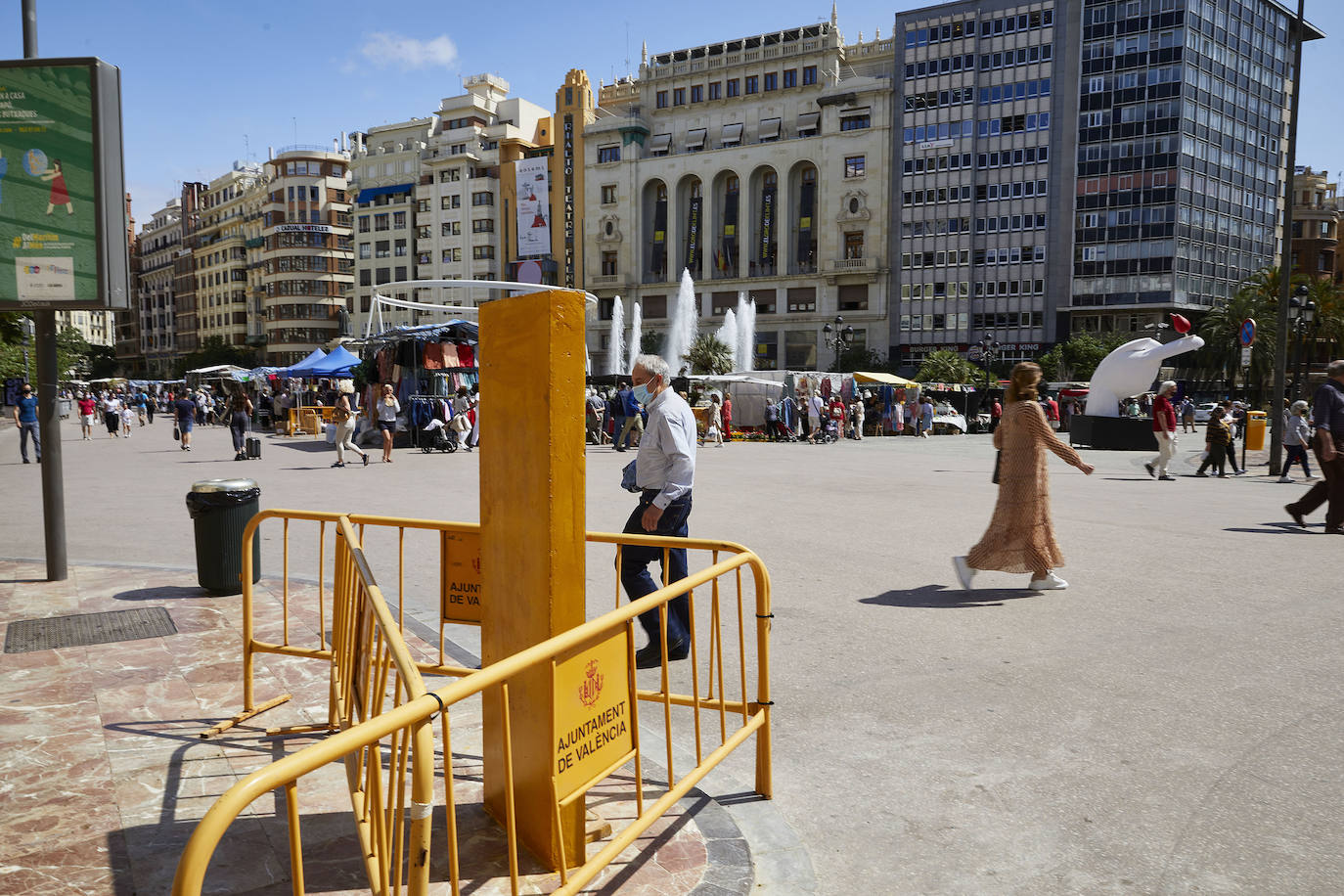 Protestas, mercadillos y restos de instalaciones se mezclan junto a la plaza del Ayuntamiento. Comerciantes y vecinos de la zona insisten en los problemas para acceder en coche mientras el monolito del 15M sigue protegido por vallas.