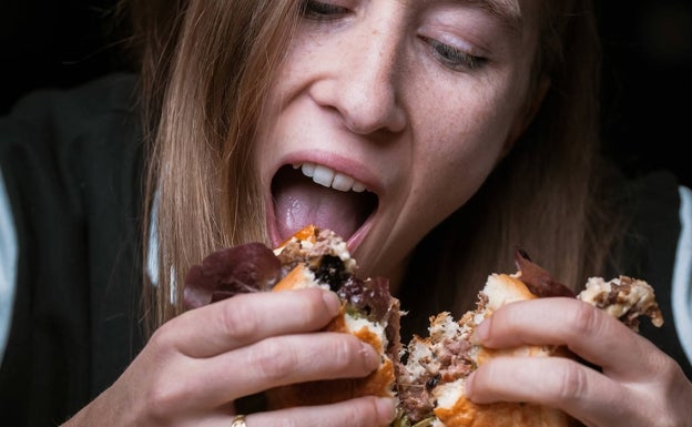 Una joven se come la hamburguesa 'Mucho Mu' que sirven en El Bar de Confianza de Altea.