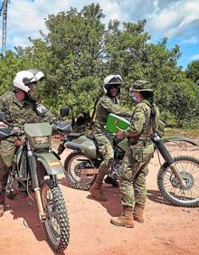 Imagen secundaria 2 - Un vehículo con un helicóptero al fondo | Habitáculos de los soldados en el ejercicio | Dos miembros conversan con una soldado en el ejercicio.