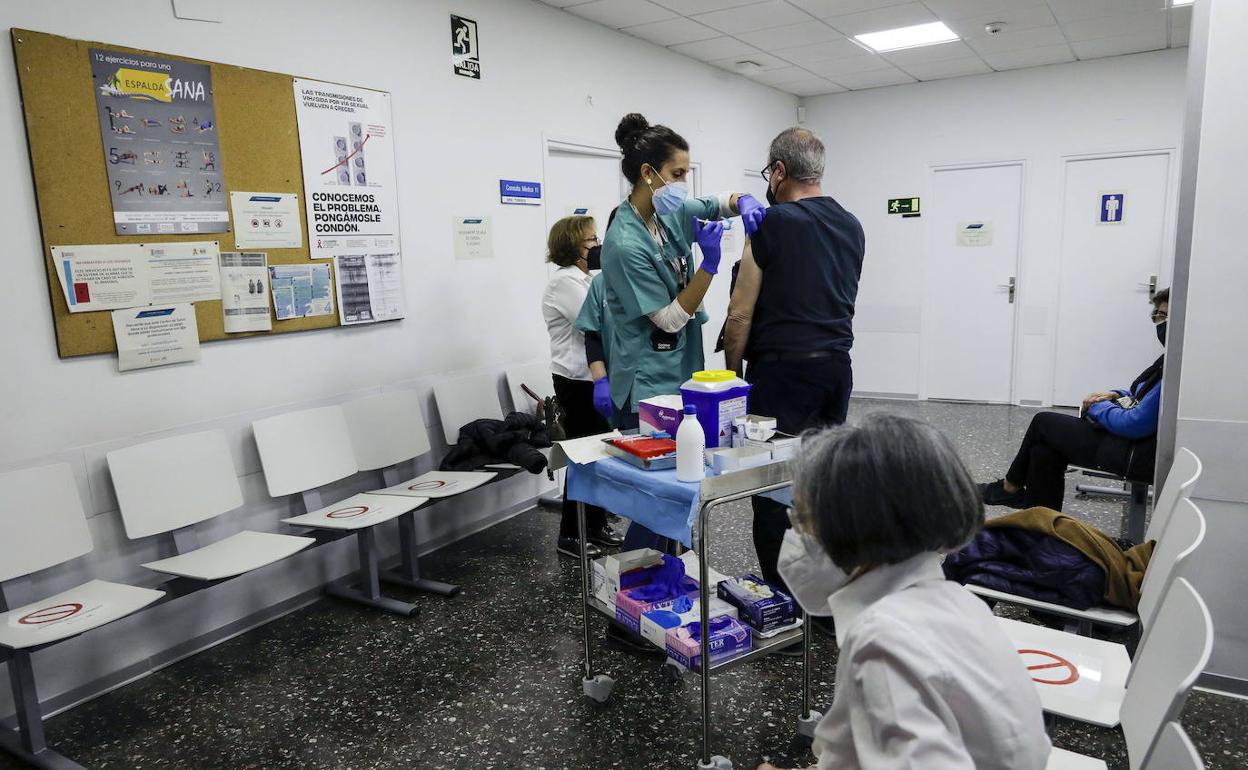 Una sanitaria vacuna a un hombre en un centro de salud. 