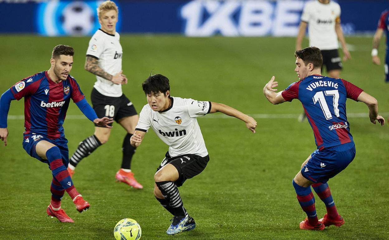 Kang In Lee avanza con el balón ante la presión de Rochina y Vukcevic durante el último derbi en el Ciutat.