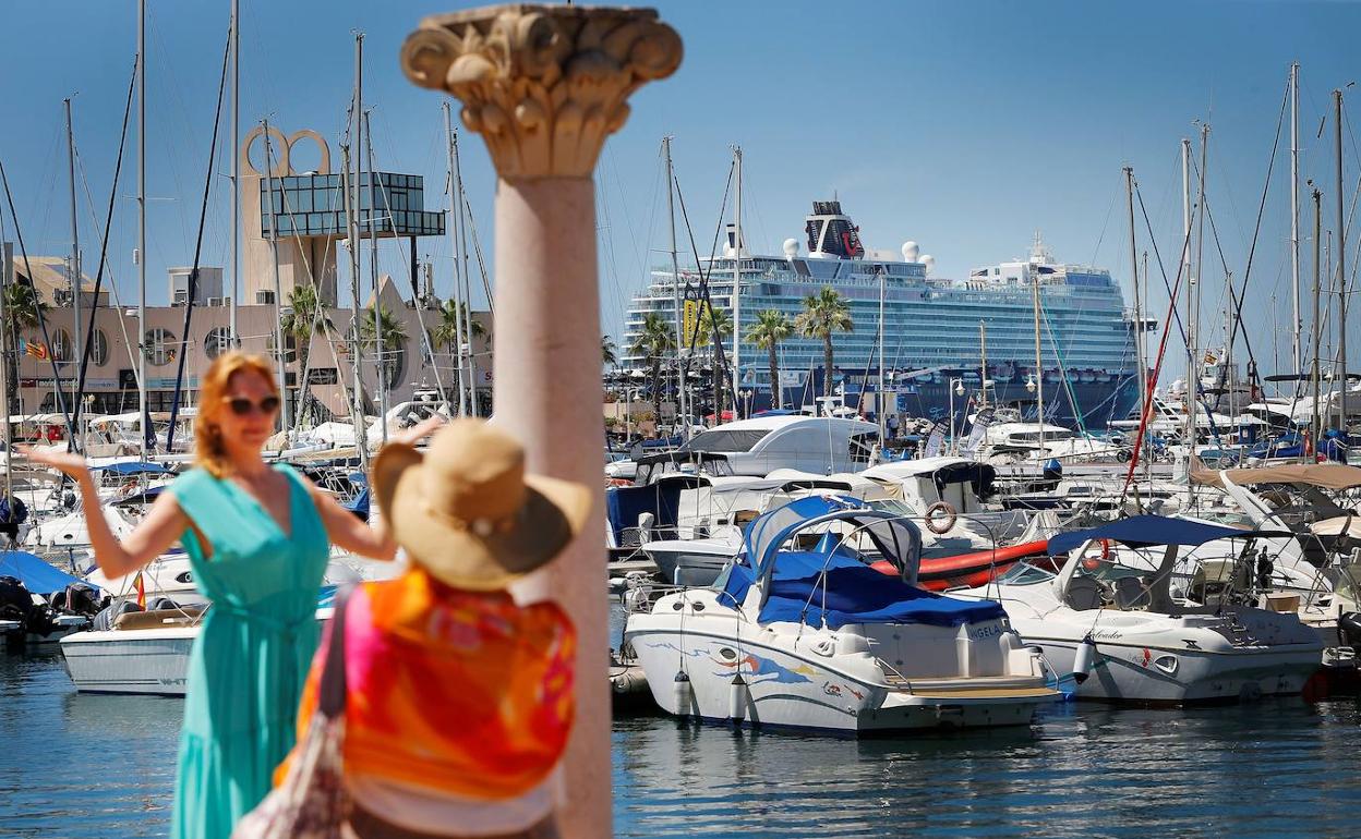 Una turista alemana se fotografía en el Puerto de Alicante con el crucero al fondo. 