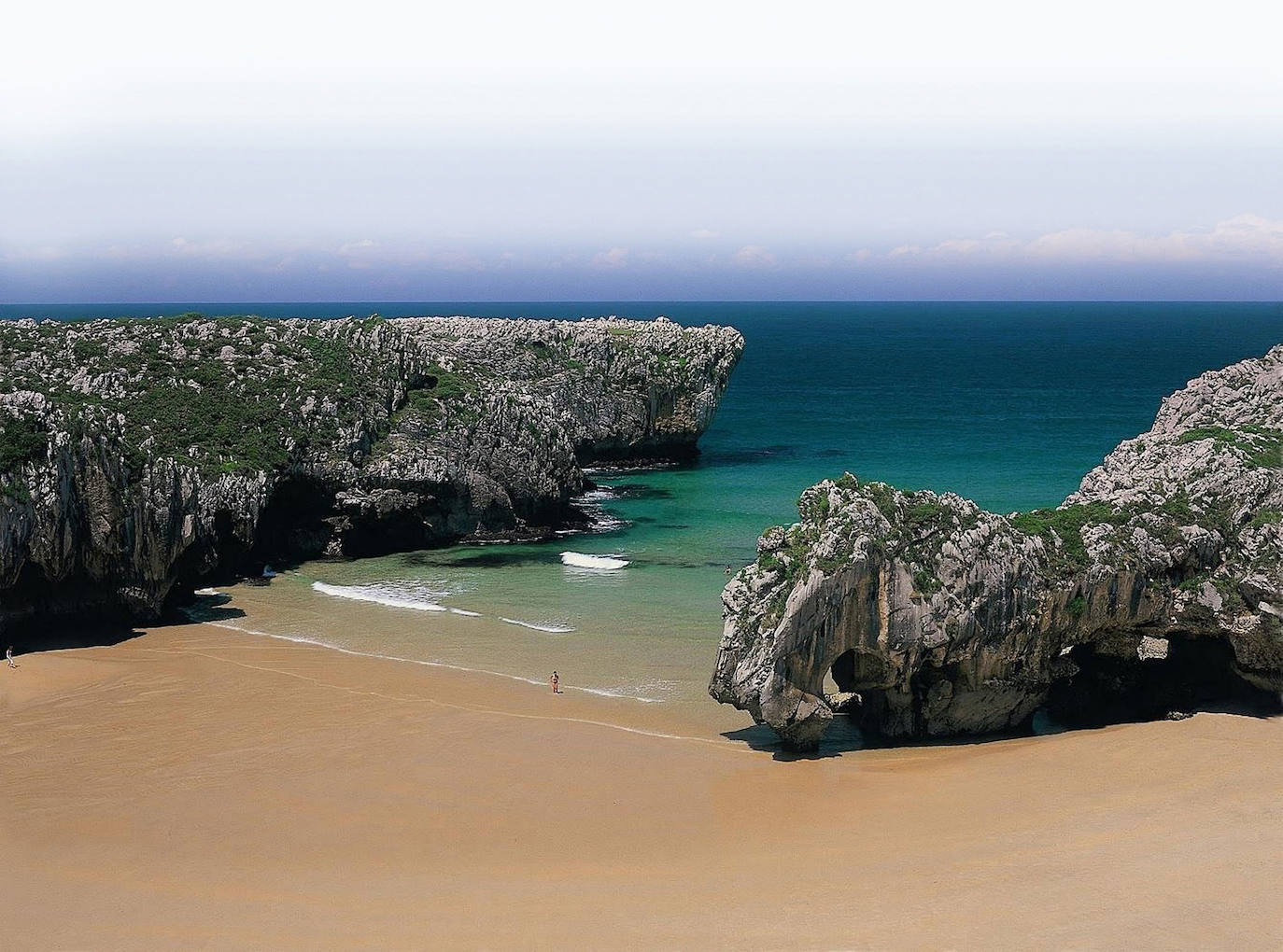 11.- Cuevas de Mar (Asturias) | En la desembocadura del río Cuevas, existe una playa salpicada por enormes formaciones rocosas perforadas por el mar que dejan al descubierto cuevas y túneles. Cuevas de Mar está formado por bolos y arena blanca, registra un oleaje moderado, aunque su baño no es peligroso, y se abre en forma triangular.