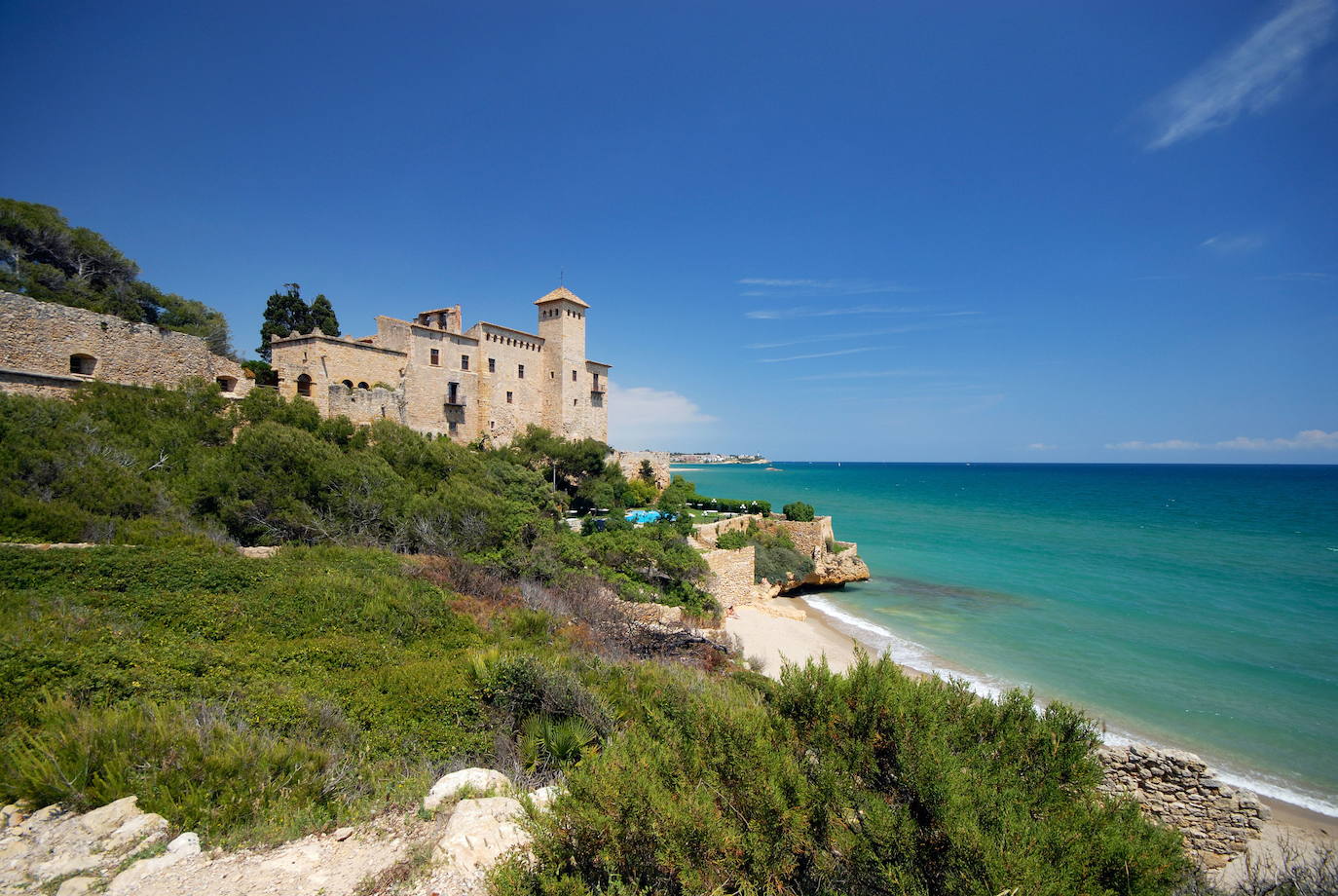 8.- Cala Jovera (Tarragona) | También llamada Cala del Castell, porque está situada a los pies del castillo de Tamarit, Jovera es una pequeña cala virgen rodeada de vegetación, fundamentalmente pinares, abierta al mar a través de una franja de noventa metros de longitud por veinte de amplitud. Esta cala, de fácil acceso a pie, está formada por arena fina y dorada bañada por unas aguas cálidas y tranquilas.