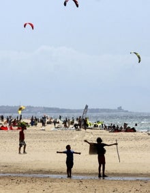 Imagen secundaria 2 - En la foto superior, el Caló des Morts, situado en la isla de Formentera. Abajo a la izquierda, la playa Rodas, perteneciente a las Islas Cíes. Abajo a la derecha, niños observan a personas hacer kitesurfing. 