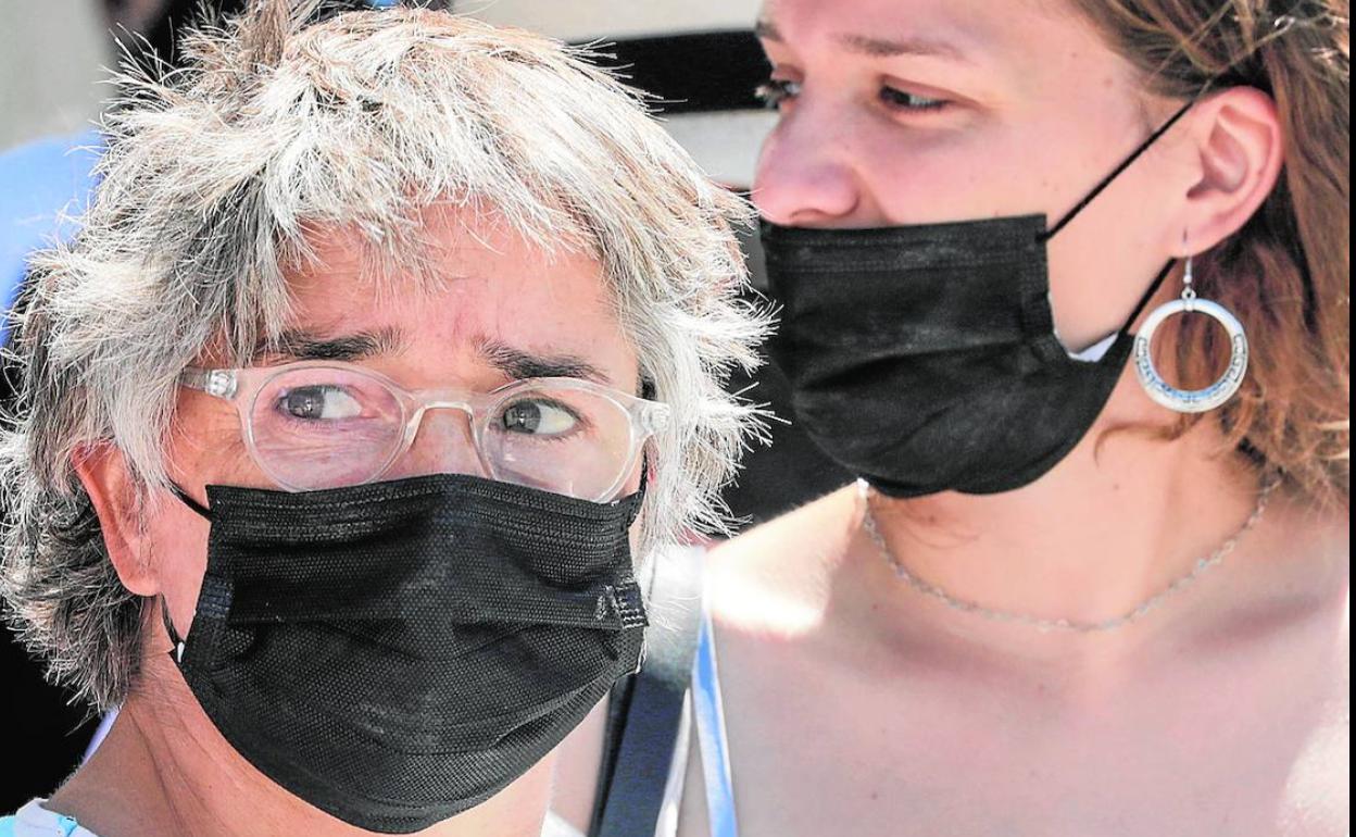 Dos mujeres se protegen del virus en Valencia con mascarillas en sus rostros.