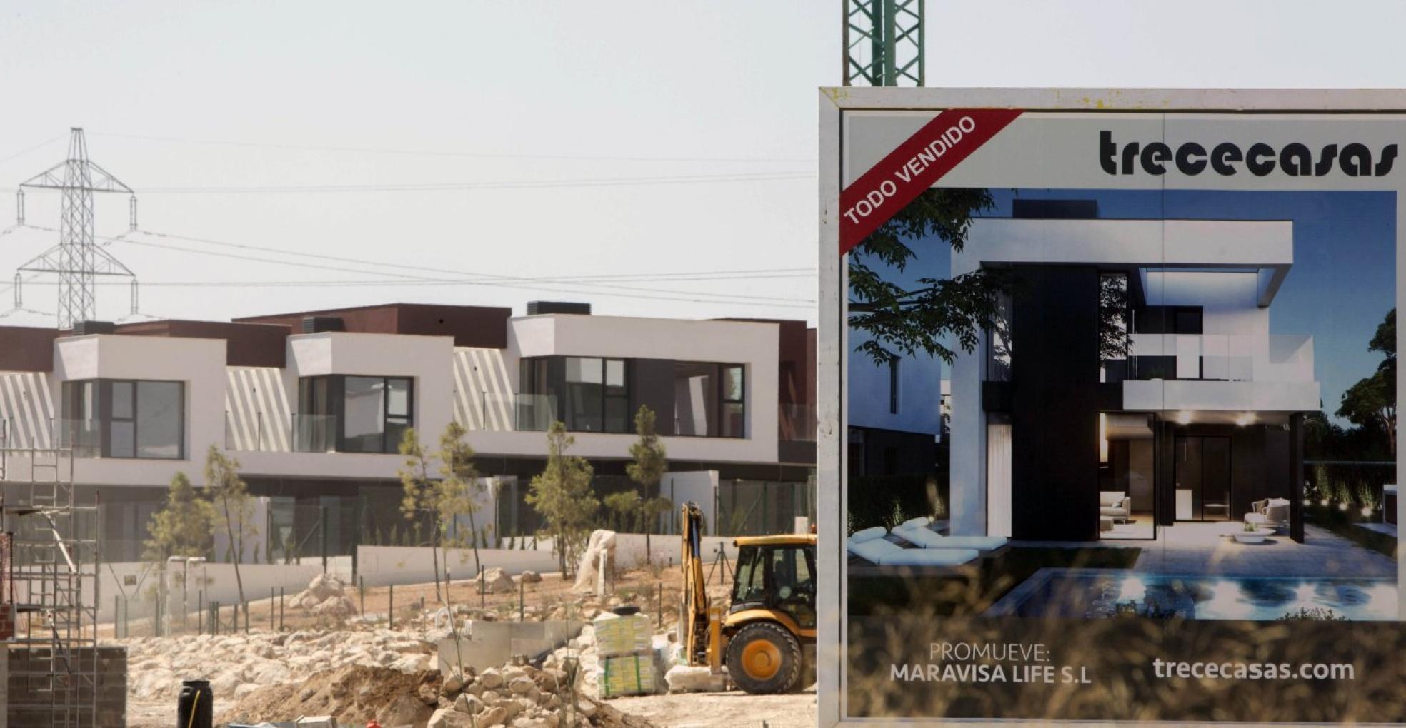 Trabajan en la construcción de más viviendas en La Conarda, junto al cartel promocional que señala que están todas vendidas . 