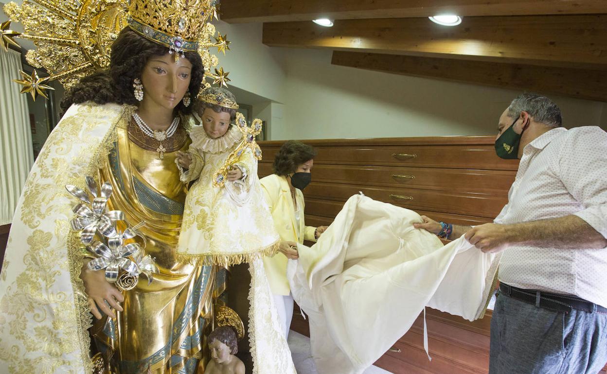 La camarera de la Virgen, María Dolores Alfonso, y Francisco Perales, responsable del taller Bordados Perales, doblan un manto ante la imagen peregrina de la Mare de Déu. 