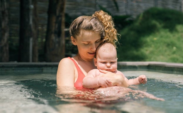 Una madre con su hijo en una piscina.