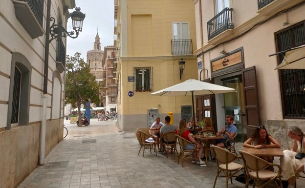 Imagen principal - Arriba, terraza de la cafetería Brunch Corner con vistas a la plaza de la Virgen y el Micalet. Abajo a la izquierda, puerta de la cafetería. Abajo a la derecha, mesa del Brunch Corner. 