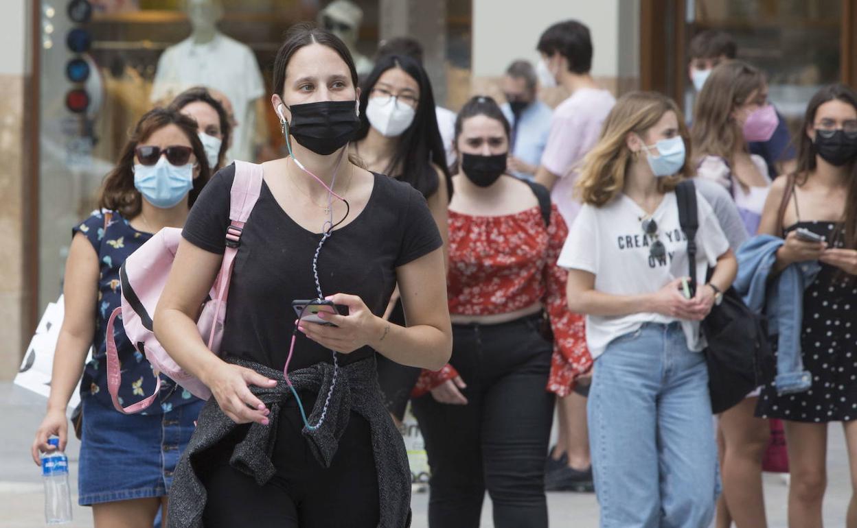 Personas con mascarilla por una calle de Valencia. 