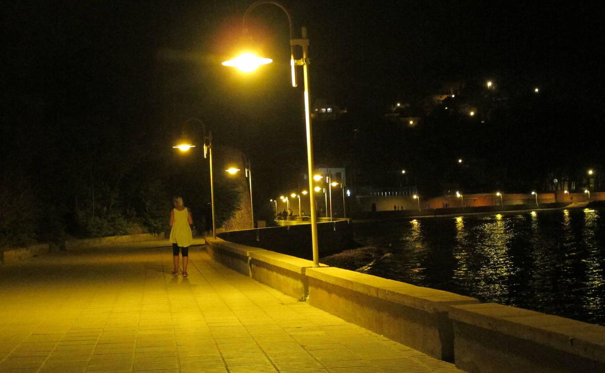 Una persona andando por la noche por el paseo de la Marineta Cassiana, en Dénia. 