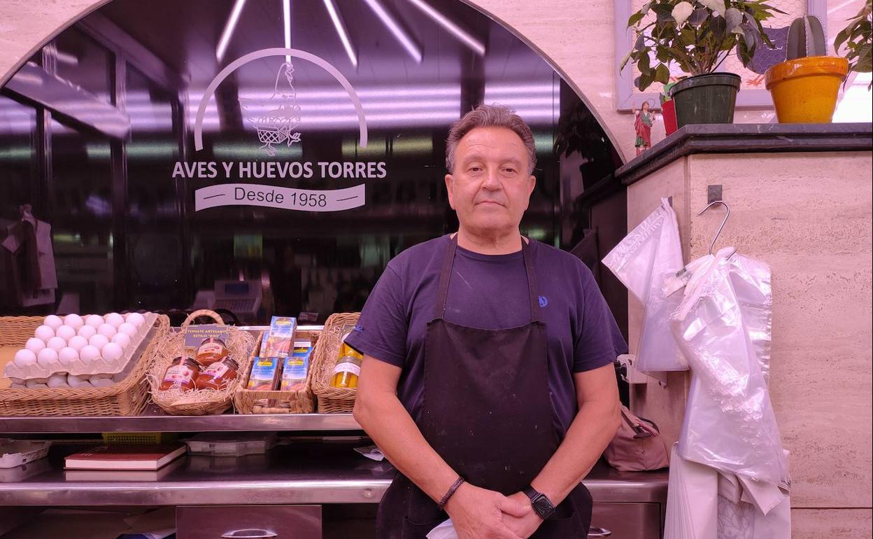 El vendedor Miguel Torres frente al logo de su negocio, Aves y huevos Torres. 