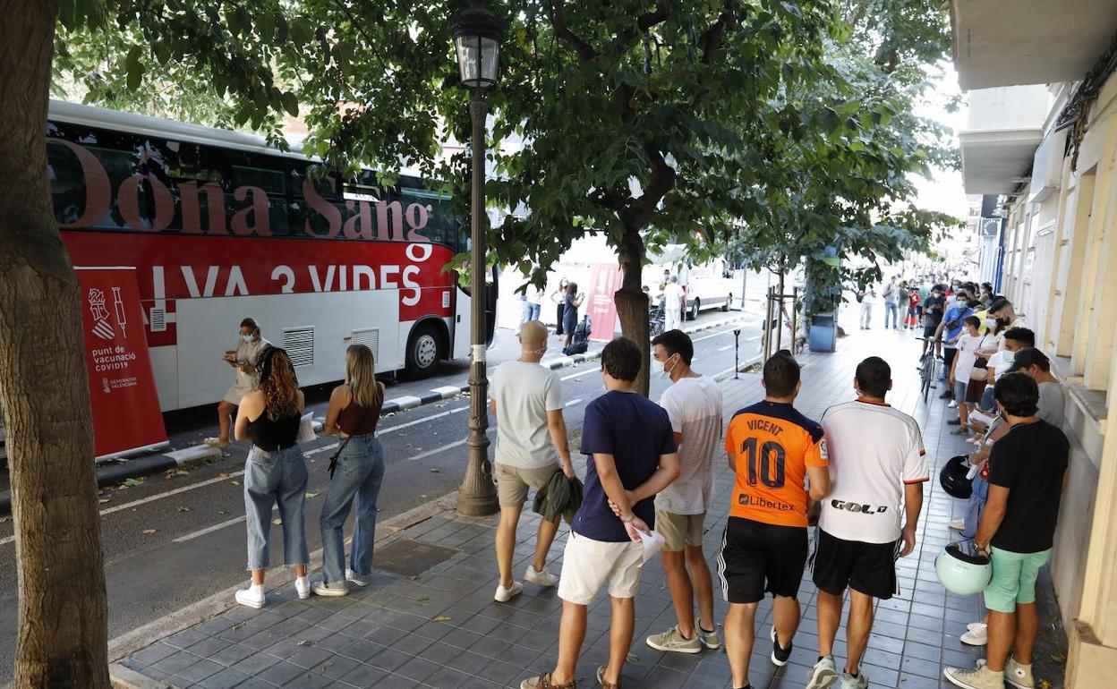 Jóvenes hacen cola para inocularse en el autobús previsto por Sanidad junto a Mestalla este domingo.