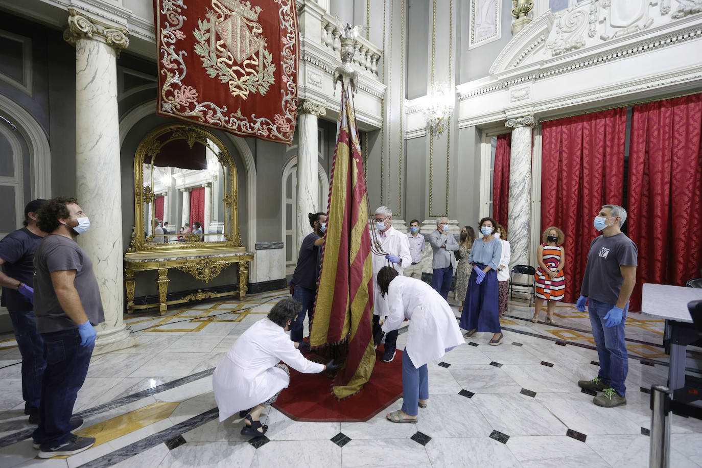 Cuatro meses de restauración devuelven el brillo a la enseña de 1928, que procesionará el 9 d'Octubre. Los expertos comprueban que el azul grisáceo que corona la pieza responde al mismo tono que muestra la bandera del siglo XVI