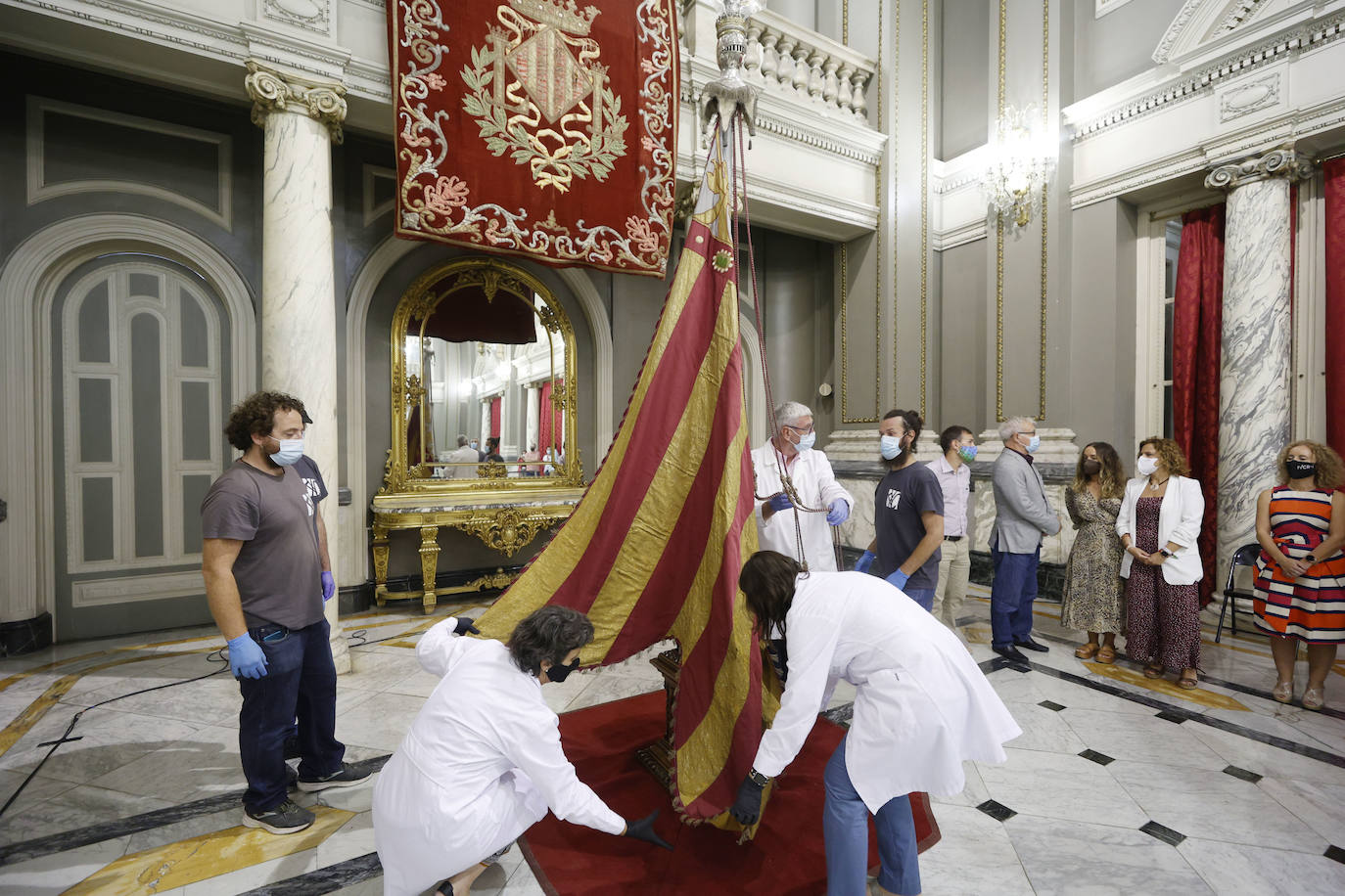 Cuatro meses de restauración devuelven el brillo a la enseña de 1928, que procesionará el 9 d'Octubre. Los expertos comprueban que el azul grisáceo que corona la pieza responde al mismo tono que muestra la bandera del siglo XVI