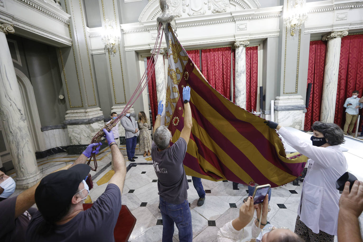 Cuatro meses de restauración devuelven el brillo a la enseña de 1928, que procesionará el 9 d'Octubre. Los expertos comprueban que el azul grisáceo que corona la pieza responde al mismo tono que muestra la bandera del siglo XVI