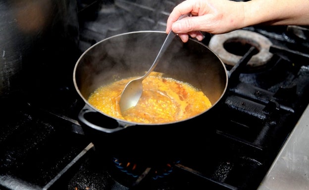 La cocción del arroz con el caldo del puchero en una cazuela de hierro. 