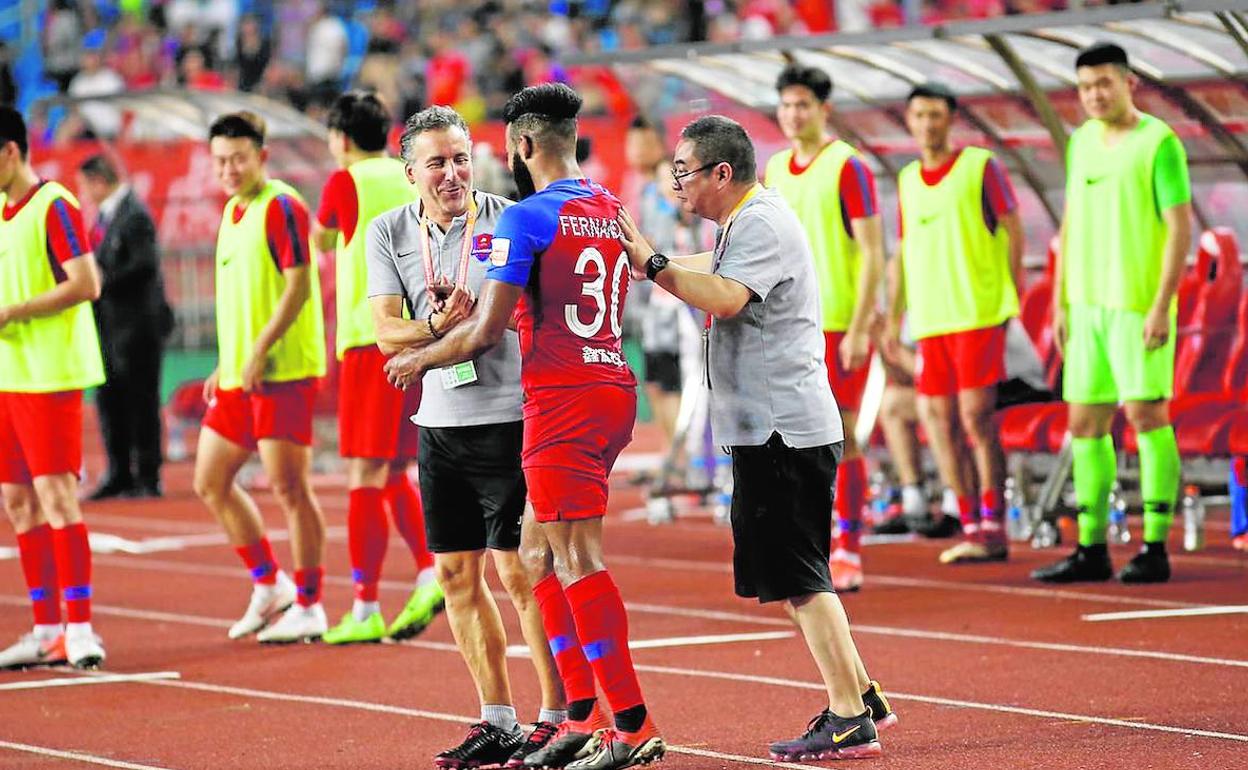 Javi Pereira choca la mano con su jugador, cuando militaba como segundo entrenador del Chongqing Liangjiang.