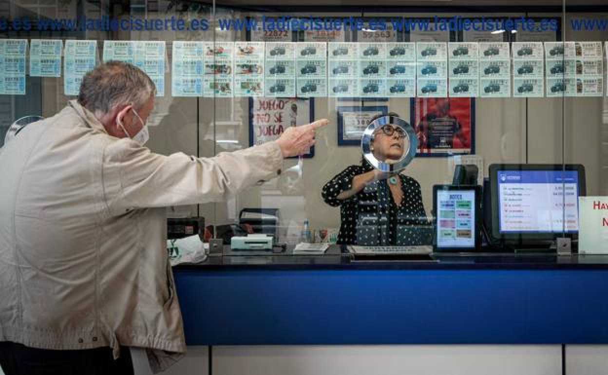 Un hombre compra un número de lotería en una administración de Loterías y Apuestas del Estado.