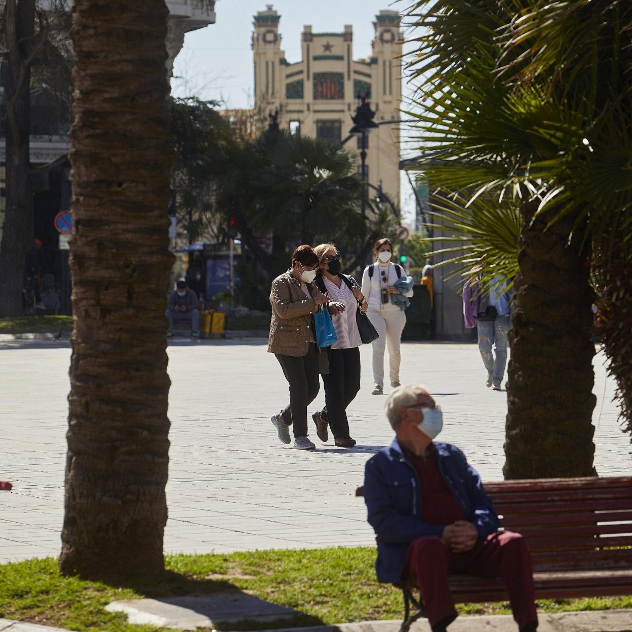 Personas, con la mascarilla puesta, pasean por la plaza del Ayuntamiento de Valencia. iván arlandis
