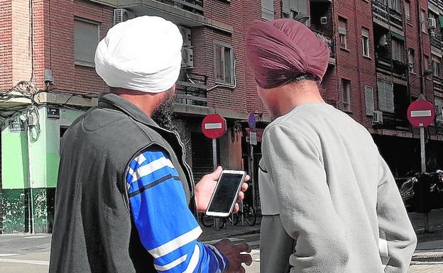 Vecindad. Dos vecinos del barrio consultan el teléfono móvil en plena plaza de la Ermita en Orriols.