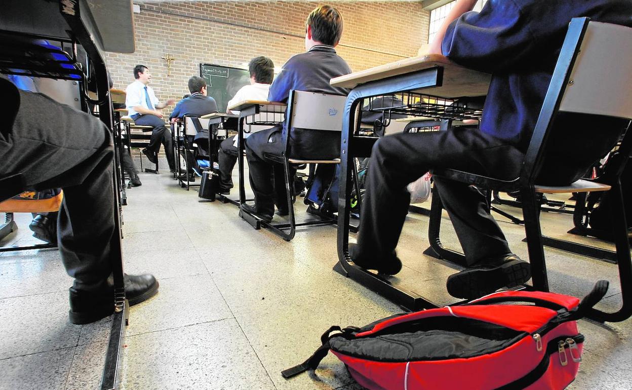 Alumnos escuchan a un profesor en una clase. 